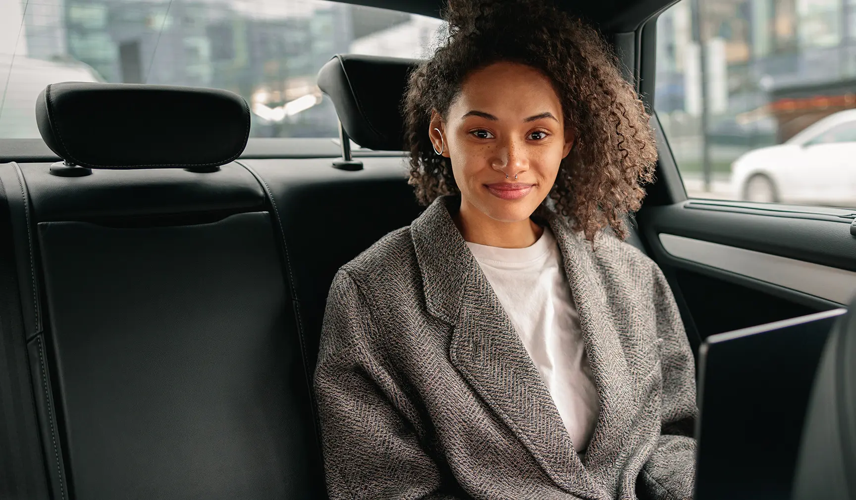 Beautiful lady sitting in back of a car with laptop